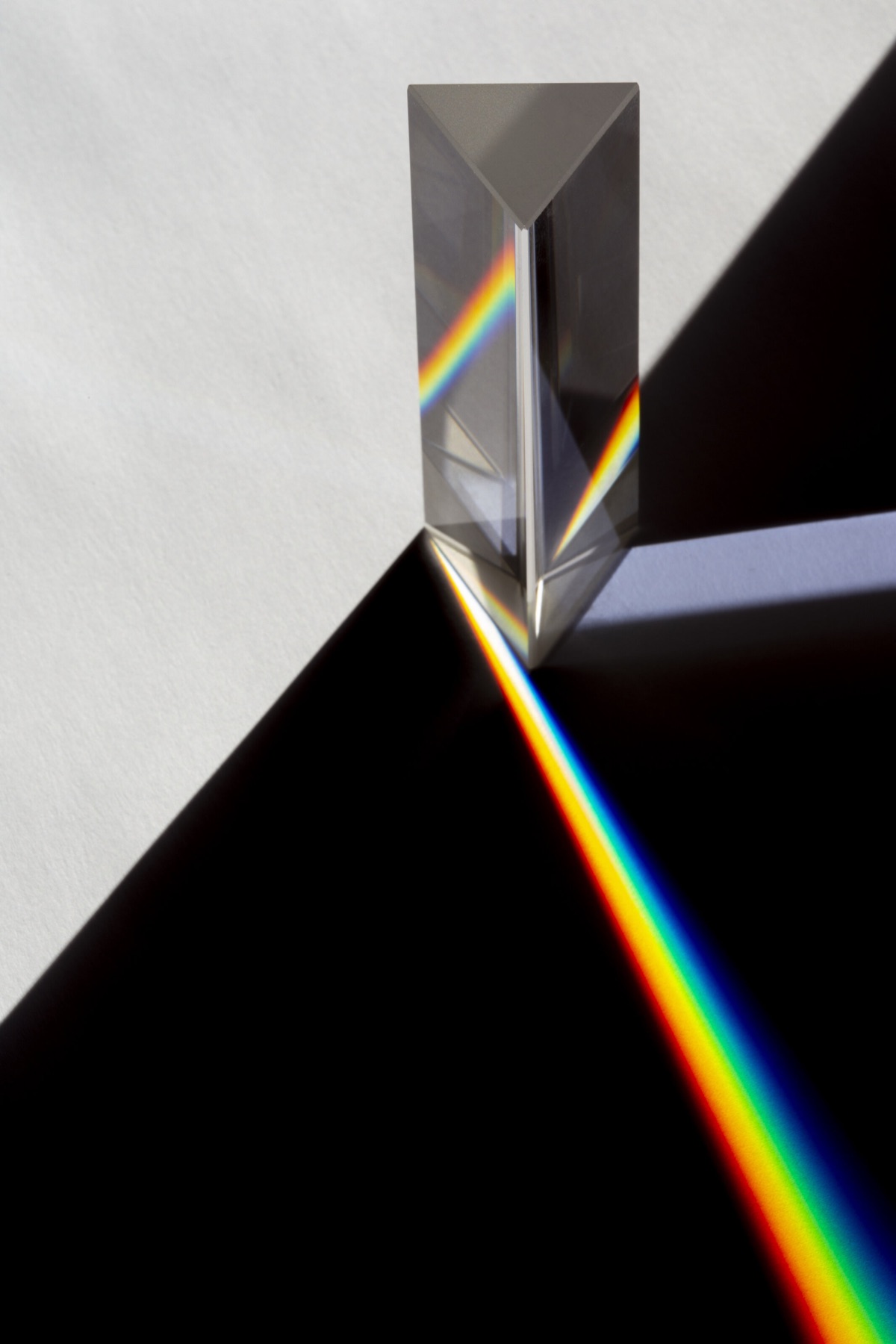 Glasprisma auf dunklem Grund, das Sonnenlicht in ein Spektrum zerlegt